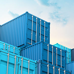 blue freight containers stacked on top of one another with a partially clear sky above