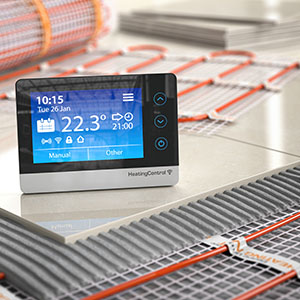 a digital thermostat sitting on top of a floor currently being installed with underfloor heating pipes