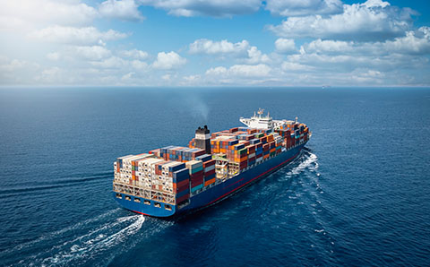 a freight ship transporting stacked cargo over the sea